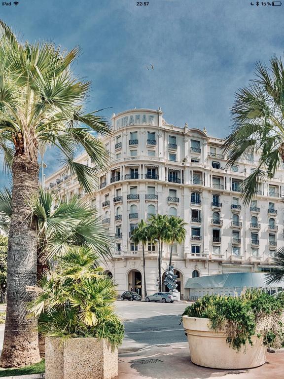 un grand bâtiment blanc avec des palmiers devant dans l'établissement La Croisette - Superbe studio au mythique Palais Miramar, à Cannes