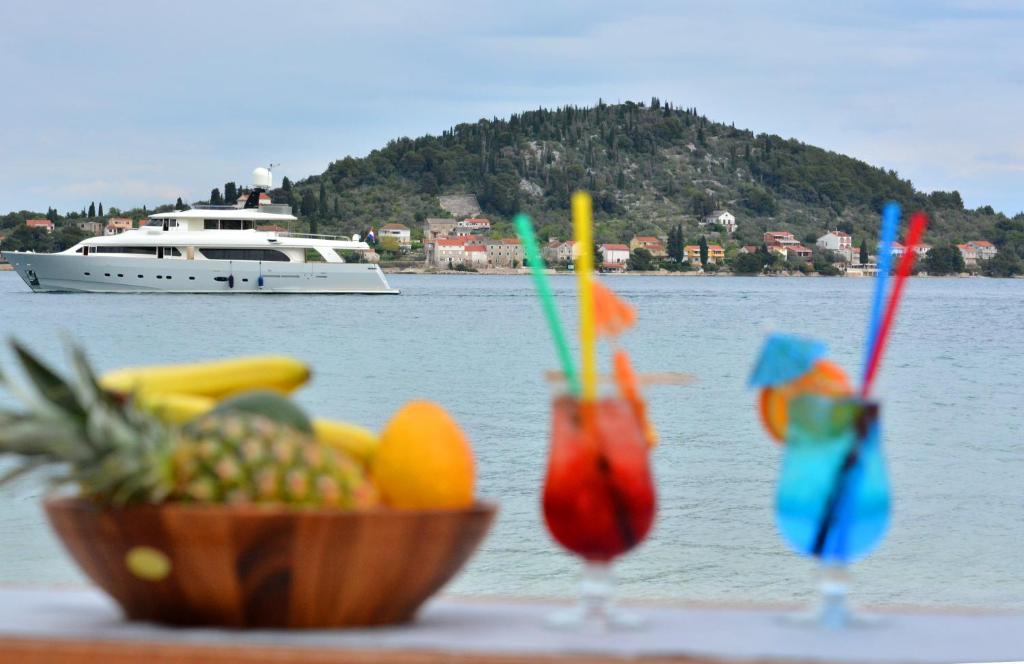 duas bebidas e uma taça de fruta numa mesa com um barco em Apartment Blue Paradise em Preko