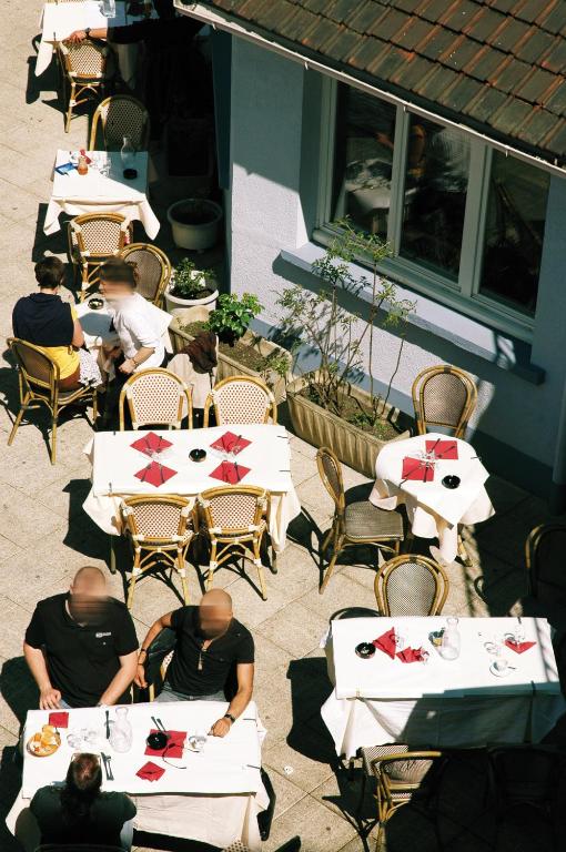 a group of people sitting at tables at a restaurant at Le Cheval Noir Hôtel Paris Pantin in Pantin