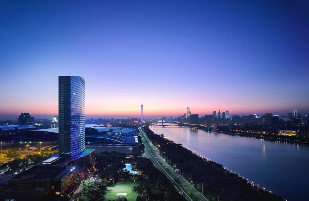 Shangri-La Guangzhou-3 minutes by walking to Canton Fair Complex في قوانغتشو: أفق المدينة مع مبنى طويل ونهر