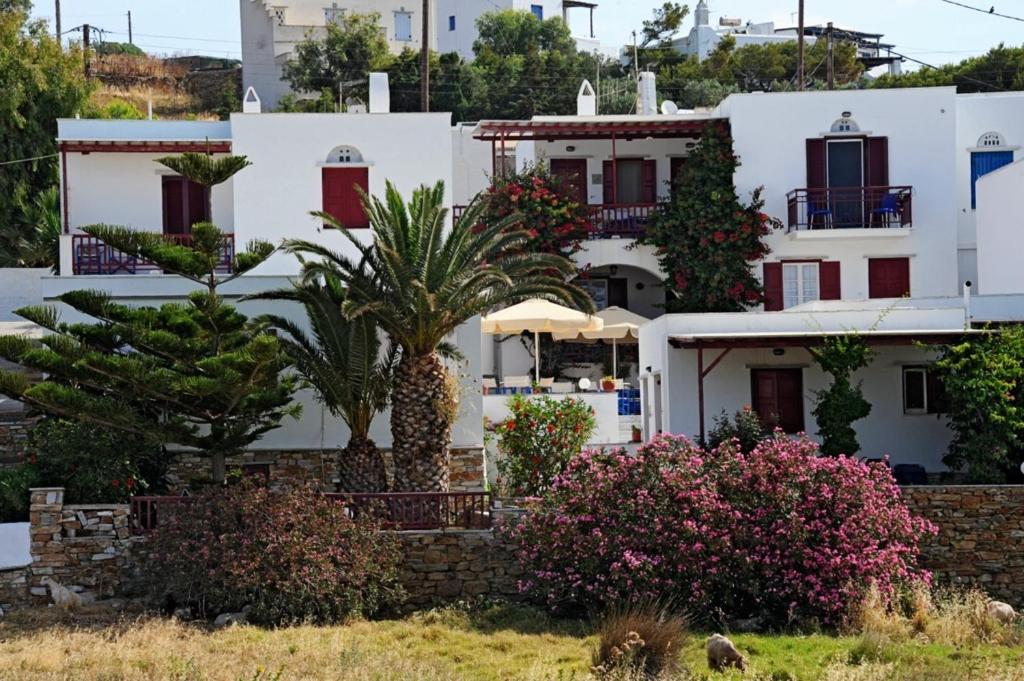 un grupo de casas blancas con palmeras y arbustos en Akrogiali Hotel en Agios Sostis