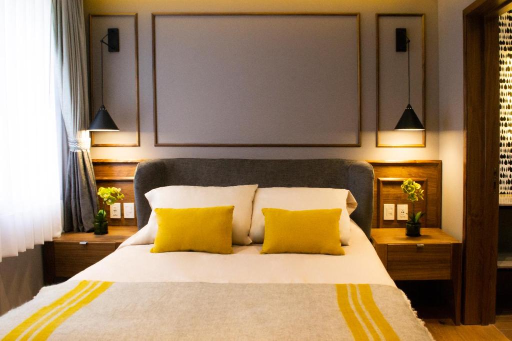 a bedroom with a large bed with two yellow pillows at Casa Bis in Mexico City