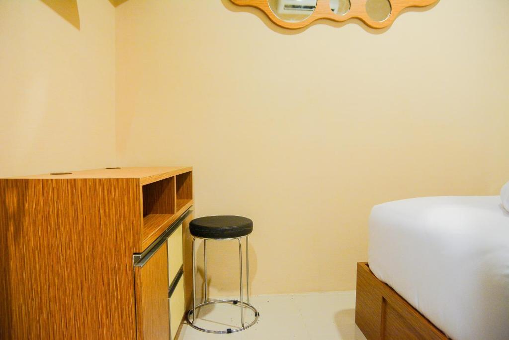 a bedroom with a bed and a stool next to a desk at Spacious 2BR GP Plaza Apartment By Travelio in Jakarta