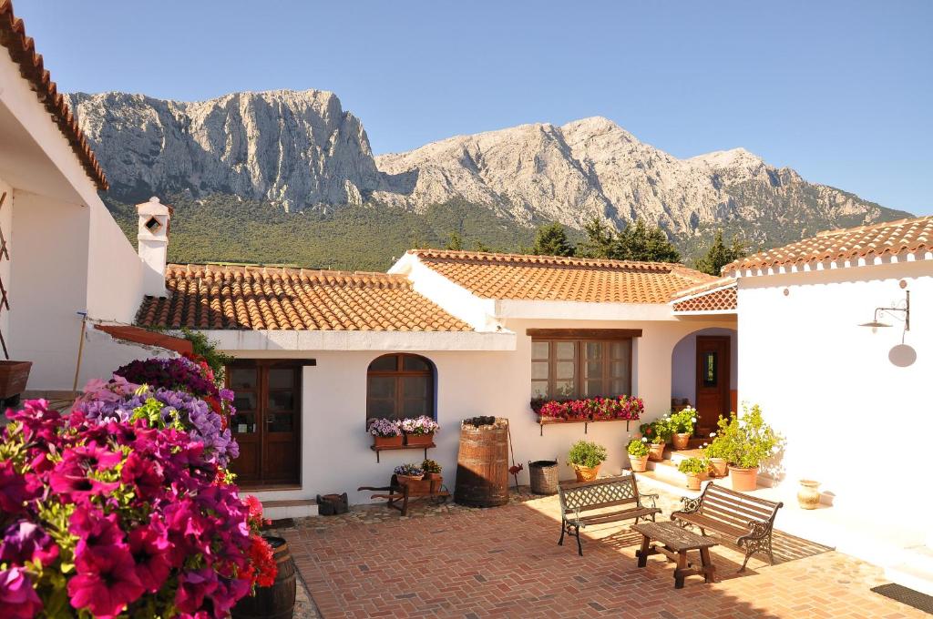 a house with flowers and mountains in the background at Agriturismo Guthiddai in Oliena