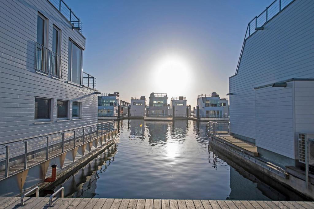 een waterlichaam tussen twee gebouwen met zonsondergang bij Schwimmendes Haus Jule in Olpenitz