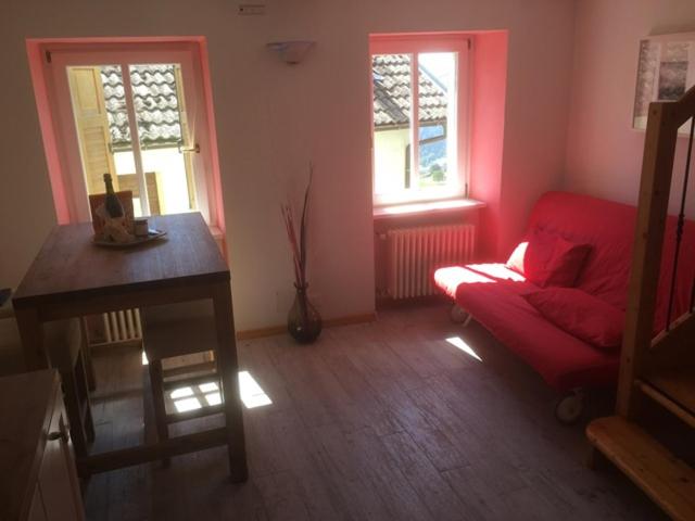 a living room with a red couch and two windows at Appartamento Dalma Foresta in Lavarone