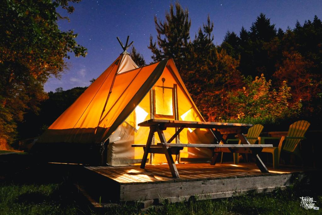 a tent with a table and chairs on a deck at Camping Le Canada-Insolite in Chiny