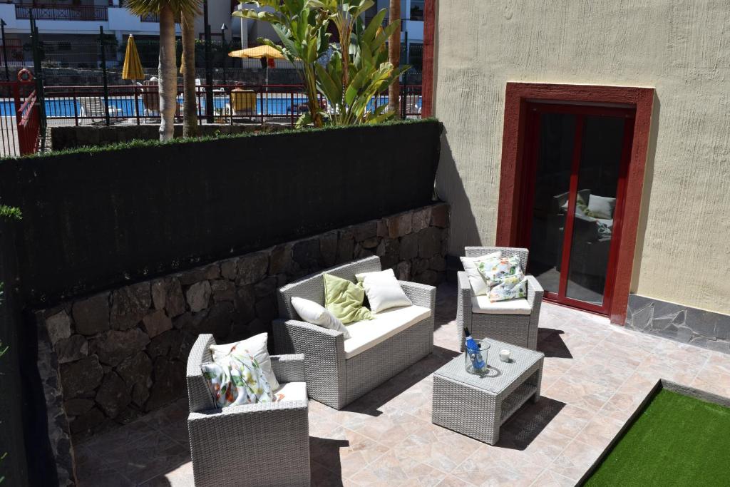 een patio met 2 stoelen, een tafel en een muur bij Andromeda in Palm-mar
