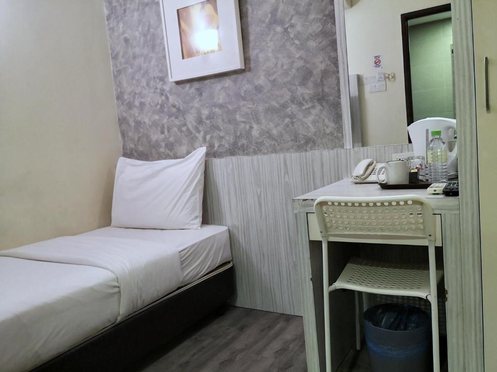 A compact single room with a small desk, tea station, wardrobe, and ensuite doorway.