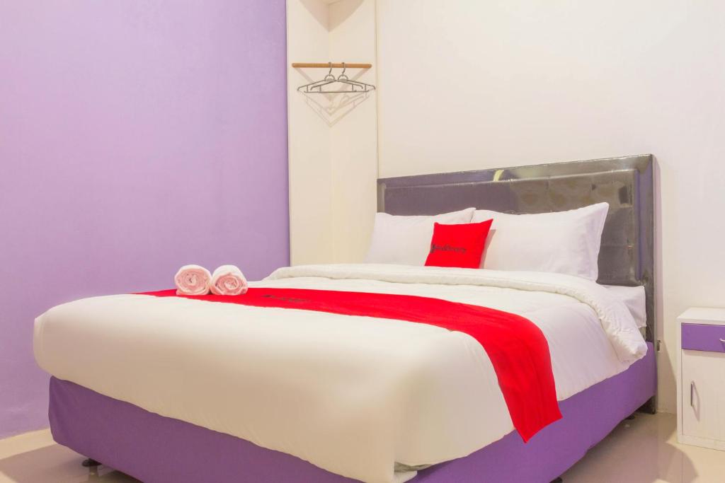 a bedroom with a large white bed with red pillows at RedDoorz Plus @ Tuparev Cirebon 2 in Cirebon