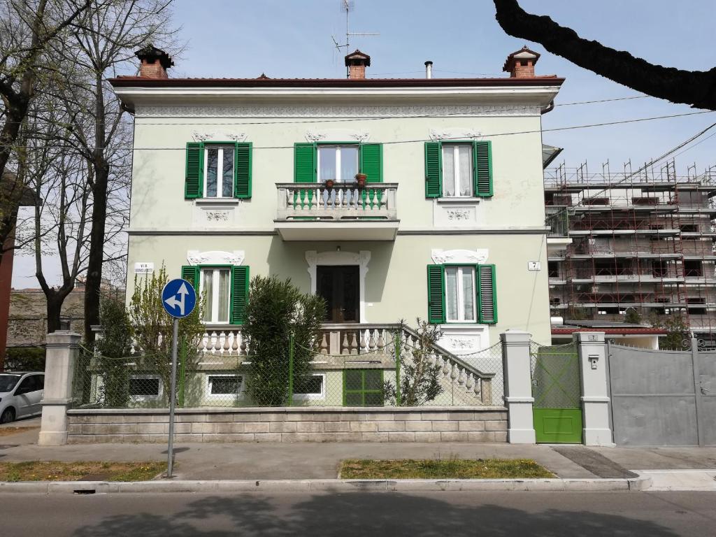 uma casa branca com persianas verdes numa rua em AGLI OLEANDRI em Gorizia