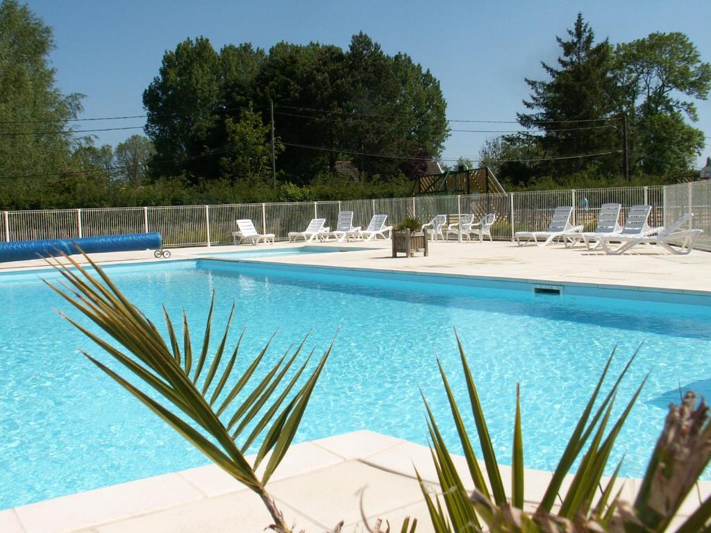 a swimming pool with chairs and a fence at Camping La Verte Prairie in Forest-Montiers