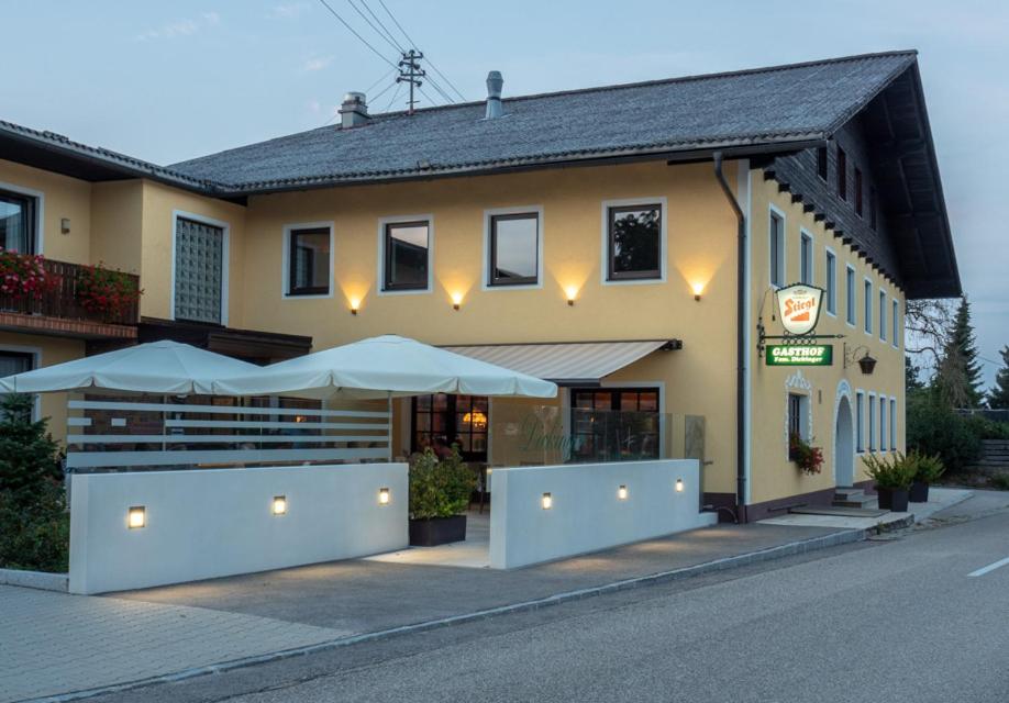 ein Gebäude mit Sonnenschirmen an der Straßenseite in der Unterkunft Gasthof Dickinger in Bad Wimsbach-Neydharting