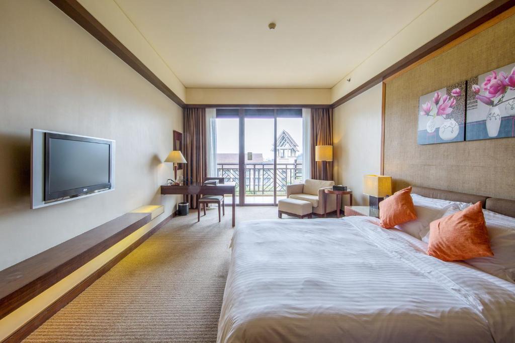 a hotel room with a bed and a flat screen tv at Dongguan Richwood Garden Hotel in Dongguan