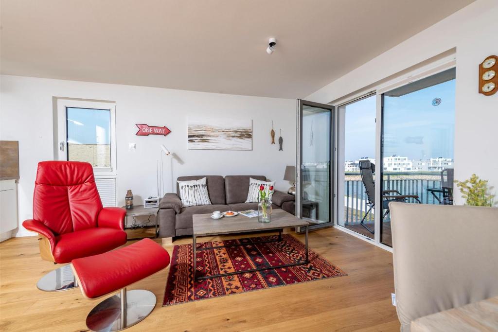 a living room with a red chair and a couch at Maria in Olpenitz