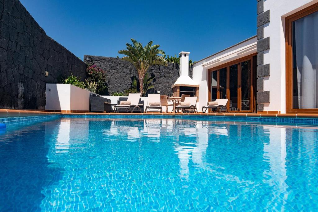 una piscina con sedie e una casa di Villa Feel a Tías