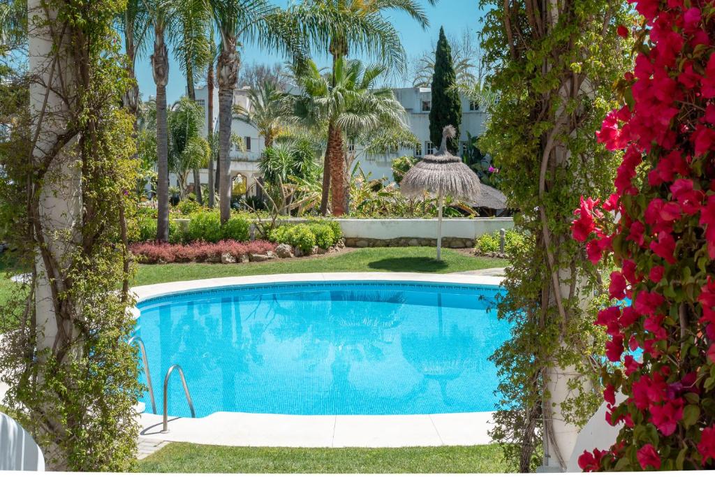a swimming pool in a yard with trees and flowers at Apartamento Marbella Real 2D in Marbella