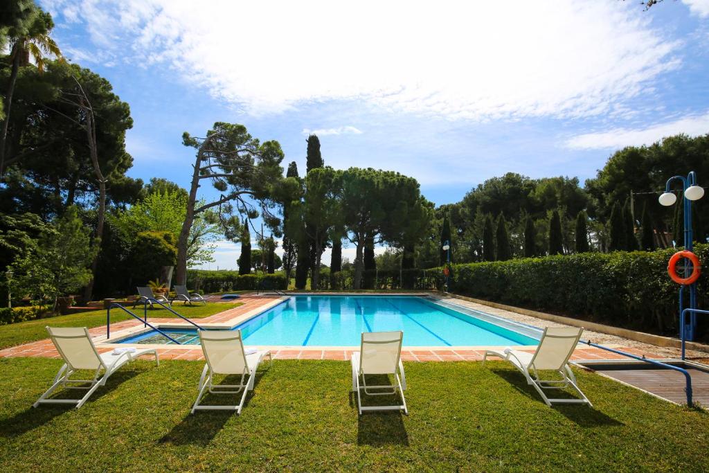 a swimming pool with lawn chairs and trees at Colonial Planet Costa Dorada in Vila-seca