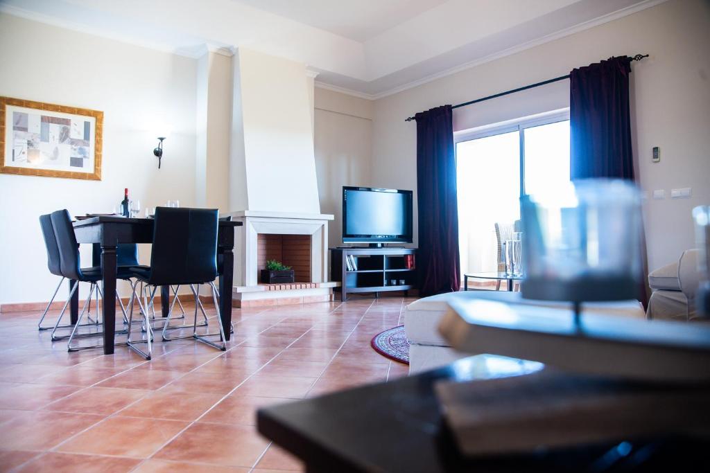 a living room with a table and chairs and a television at Colina Verde Resort in Moncarapacho