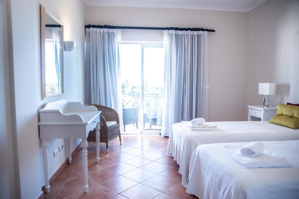 a hotel room with two beds and a piano at Colina Verde Resort in Moncarapacho