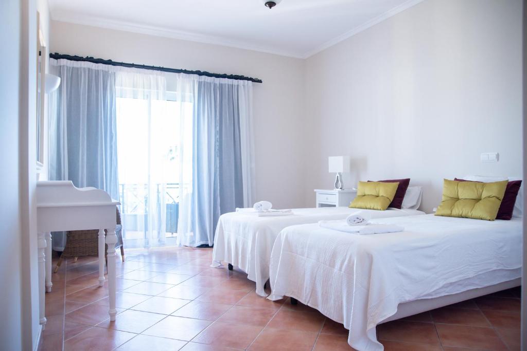a white bedroom with a large bed and a piano at Colina Verde Resort in Moncarapacho