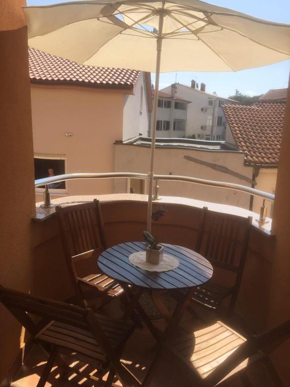 a patio table with an umbrella on a balcony at Apartment Ejla in Medulin