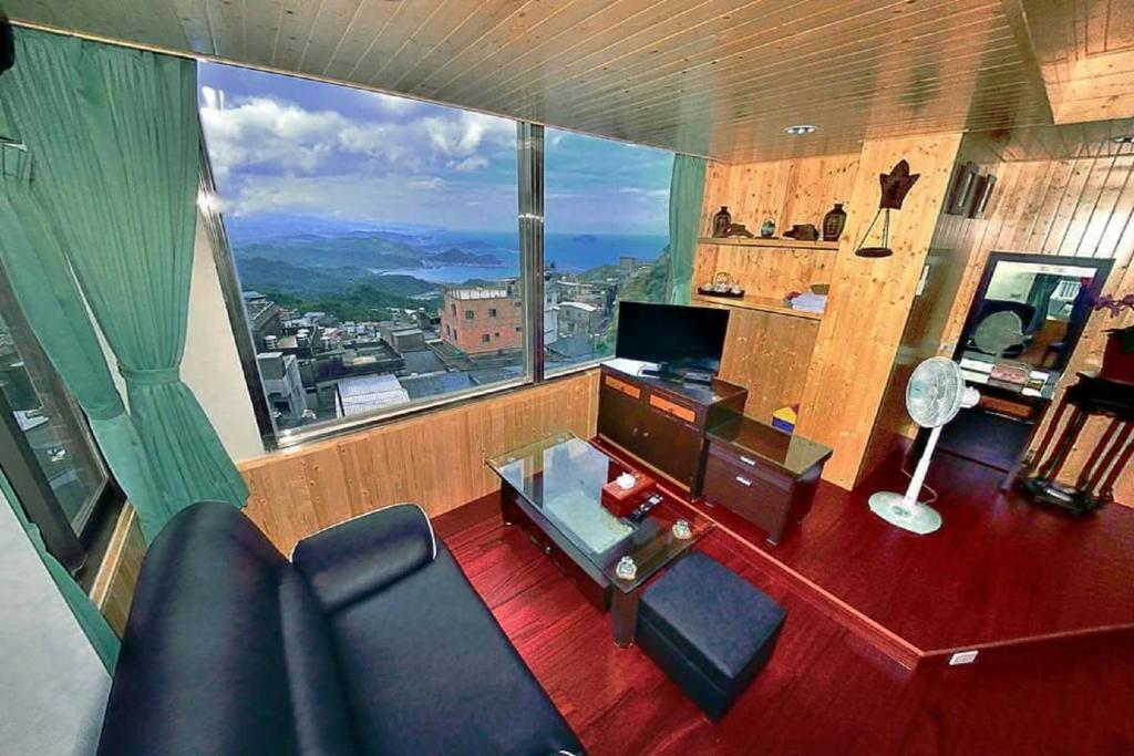 a living room with a desk and a large window at Yuan-Yee Homestay in Jiufen