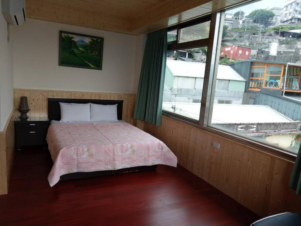 a bedroom with a bed and a large window at Yuan-Yee Homestay in Jiufen