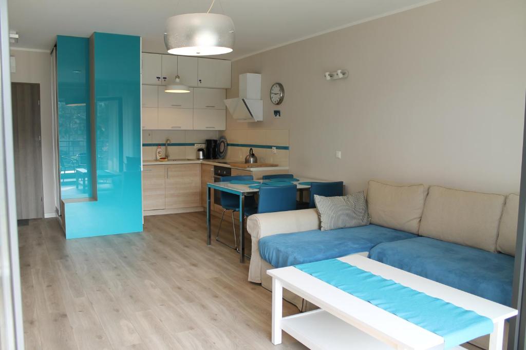 Heaven Apartament في بوغورزيلكا: غرفة معيشة مع أريكة زرقاء ومطبخ
