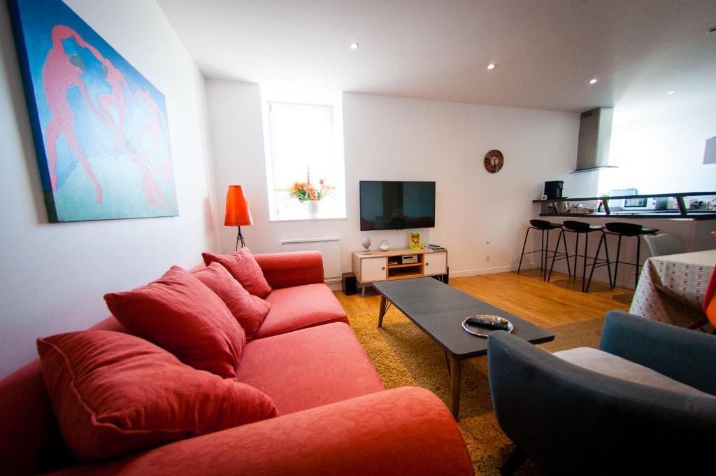 ein Wohnzimmer mit einem roten Sofa und einem Tisch in der Unterkunft Le Massilia in Vichy