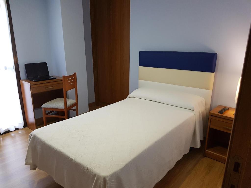 um quarto com uma cama com uma cabeceira azul e branca em HOSTAL CAMELOT em Fabero