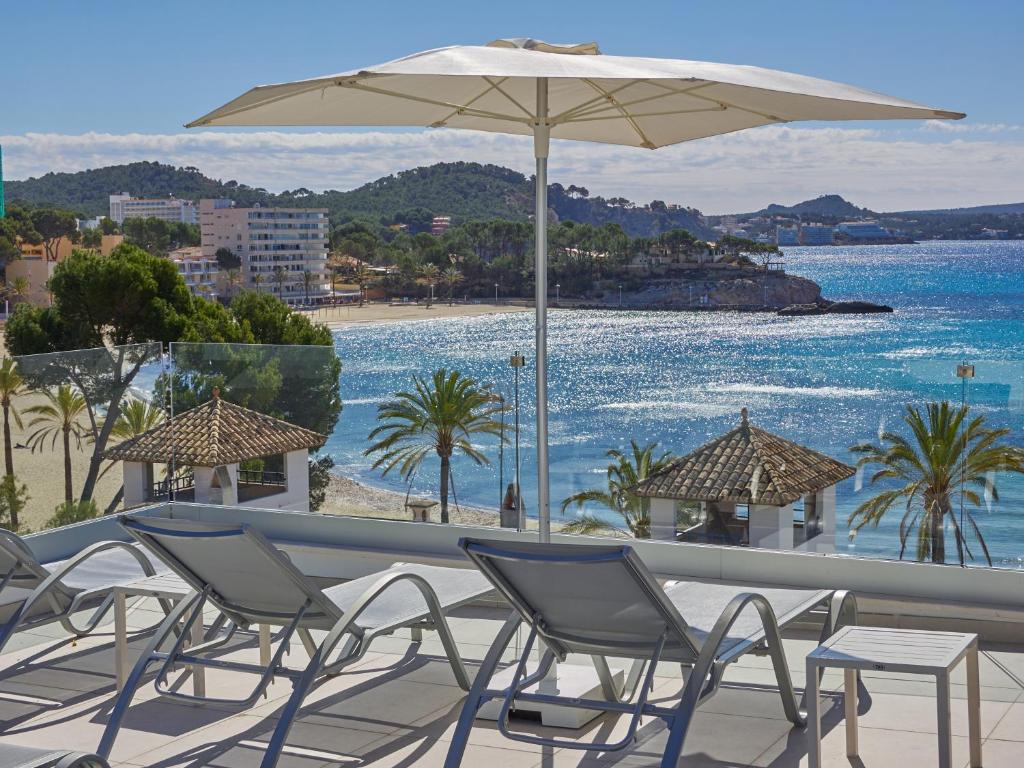 a group of chairs and an umbrella on a balcony at Paguera Treff Boutique Hotel in Paguera