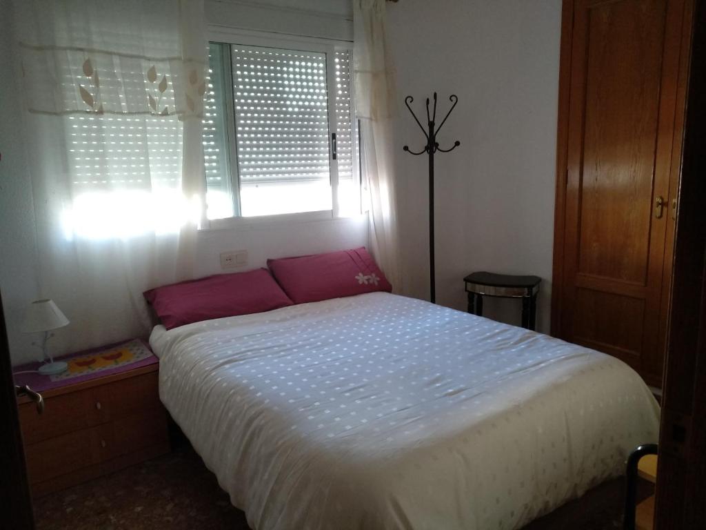 ガンディアにあるBenicanenaのベッドルーム1室(ピンクの枕が付くベッド1台、窓付)