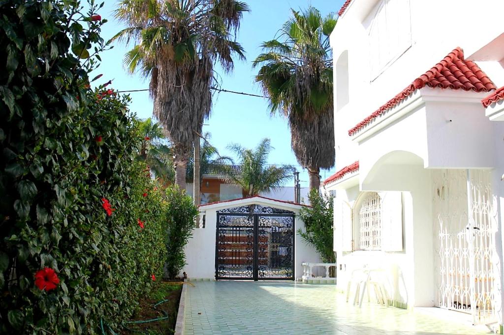 um portão para uma casa branca com palmeiras em Votre Maison de vacances en bord de mer - Harhoura em Rabat