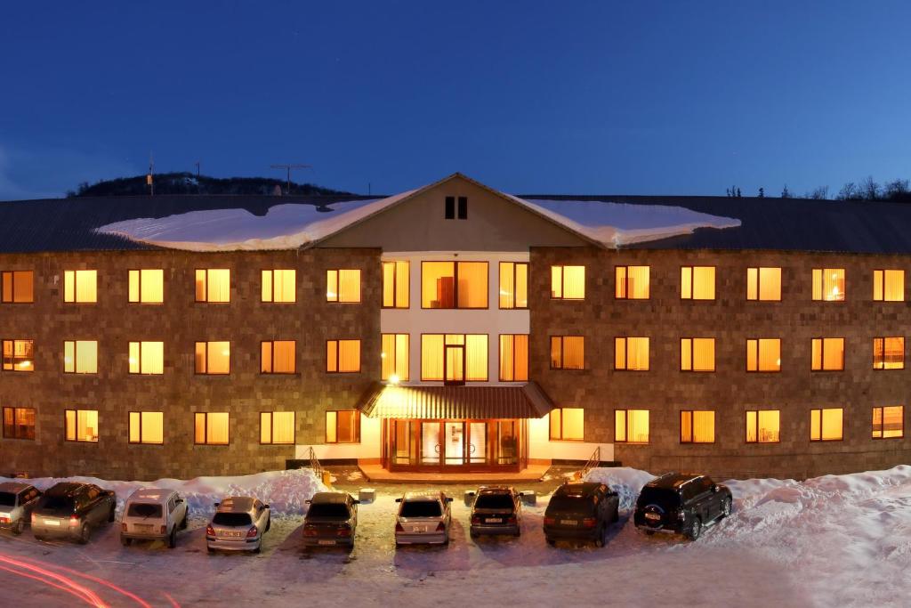 a large building with cars parked in a parking lot at University Hotel Tsakhkadzor in Tsaghkadzor