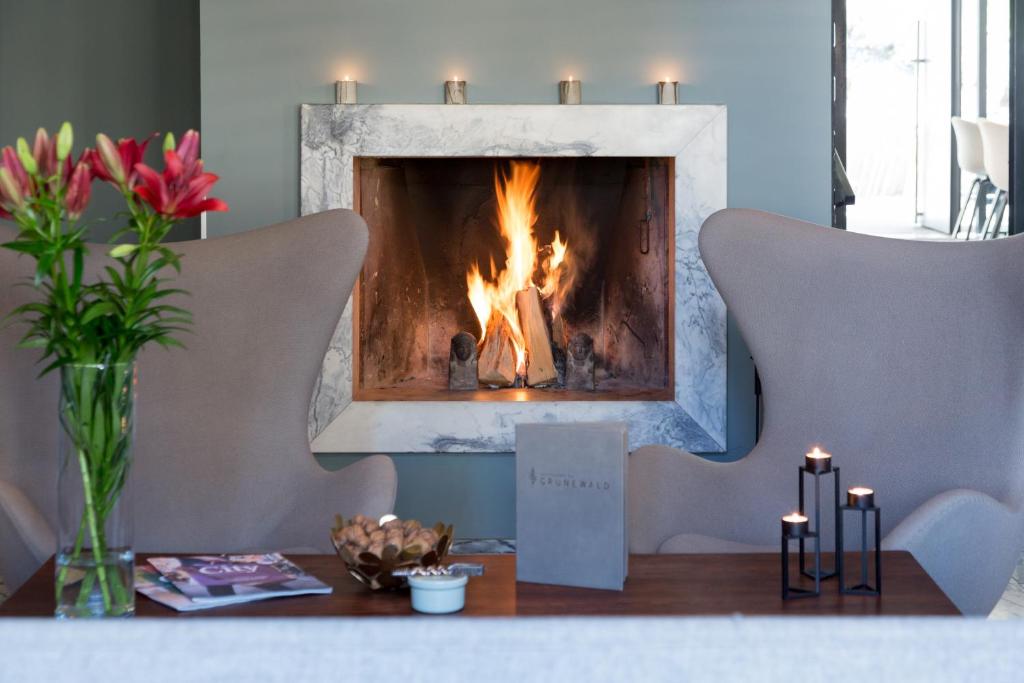 a fireplace in a living room with a table with candles at Hostellerie du Grünewald in Luxembourg