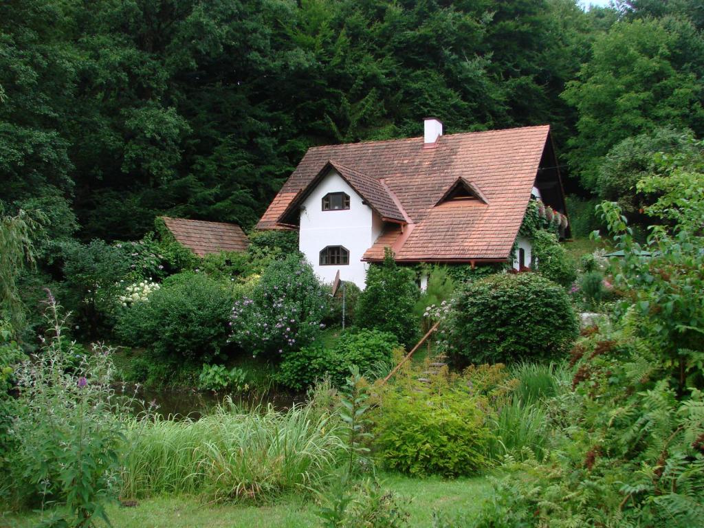 een wit huis met een rood dak in een tuin bij Ferienhaus Himmelreichmühle in Rettenberg
