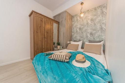 a bedroom with a blue bed with a hat on it at Apartament morski sen in Gdańsk
