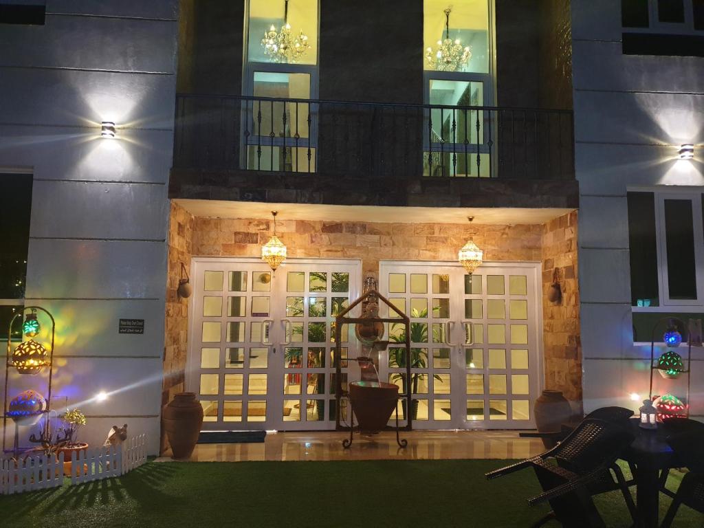 Muscat Royal Suites في سيب: منزل مع ساحة أمامية مضاءة في الليل
