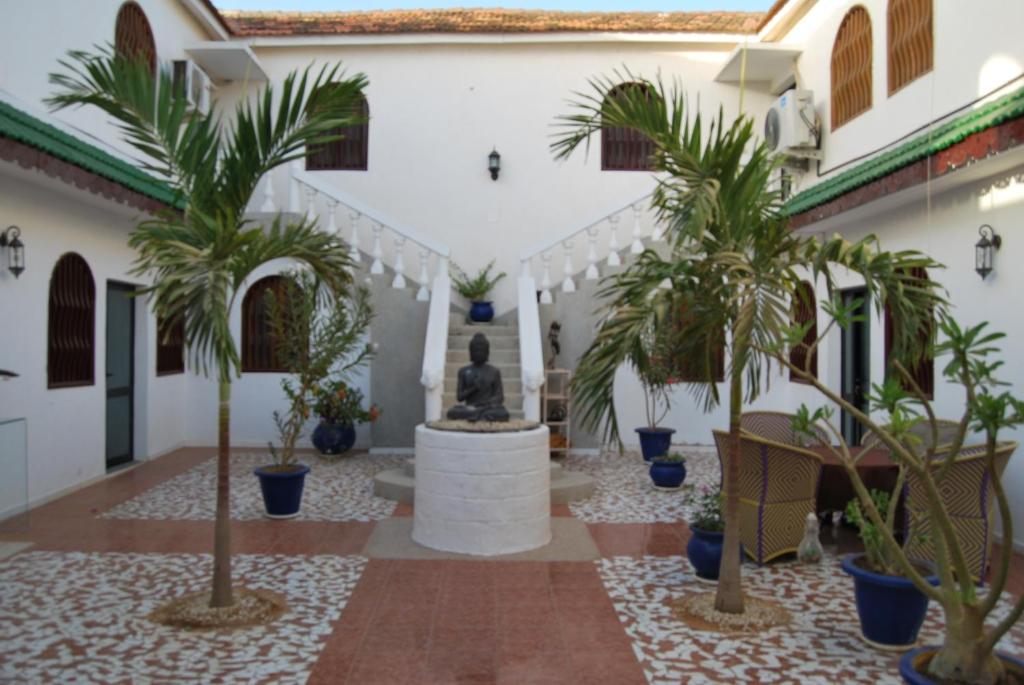 a courtyard with palm trees and a fountain at Riad côté jardin in Saly Portudal