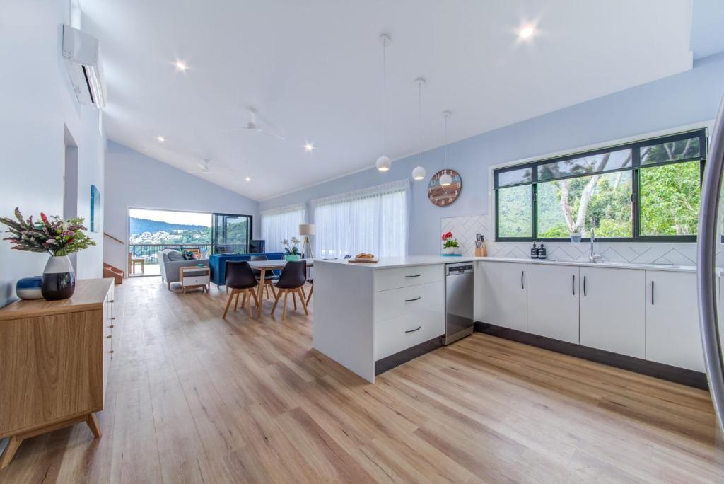 a kitchen and dining room with white cabinets and a table at Hillside Haven - Airlie Beach in Airlie Beach