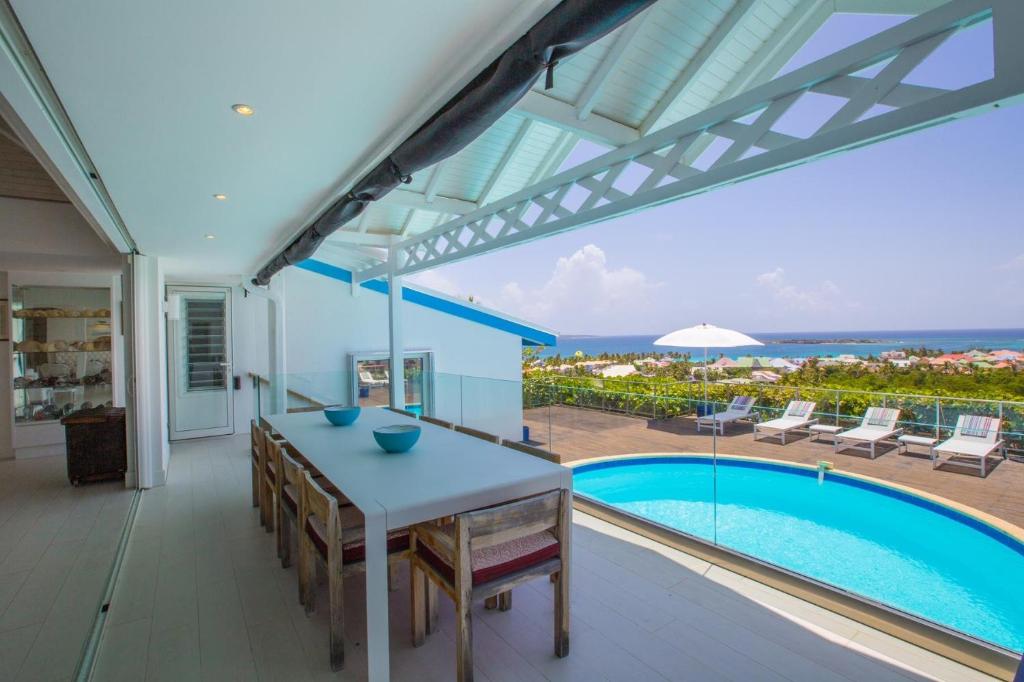 a dining room with a table and a swimming pool at Dream Villa Orient Bay 570 in Orient Bay