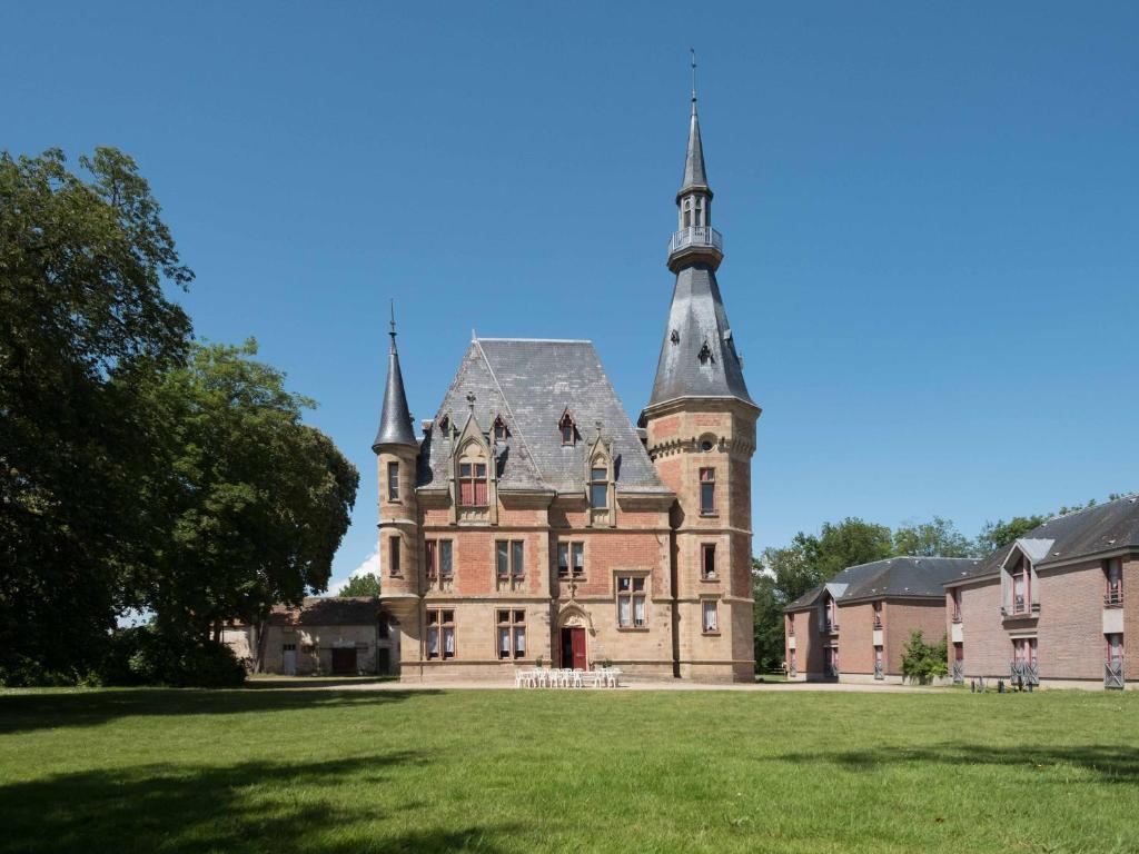 un vieux château avec une tour sur une pelouse dans l'établissement Château de Petit Bois, à Cosne-dʼAllier