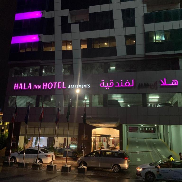 a hotel with cars parked in front of it at night at Hala Inn Hotel Apartments - BAITHANS in Ajman 
