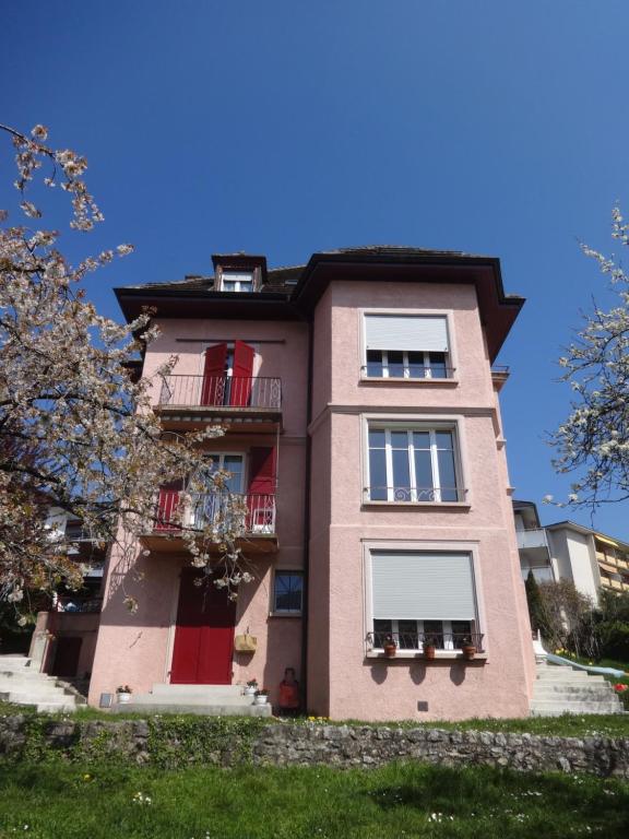 un edificio rosa con puertas y ventanas rojas en Chambres meublées Prilly - Lausanne, en Prilly