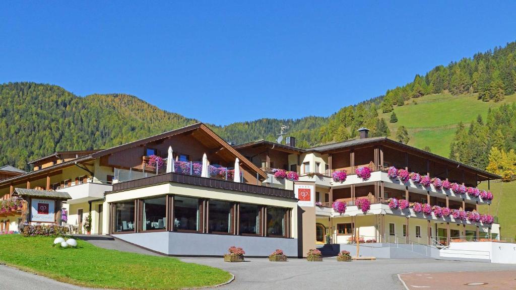 - un grand bâtiment avec des fleurs sur les balcons dans l'établissement Hotel Trenker, à Braies