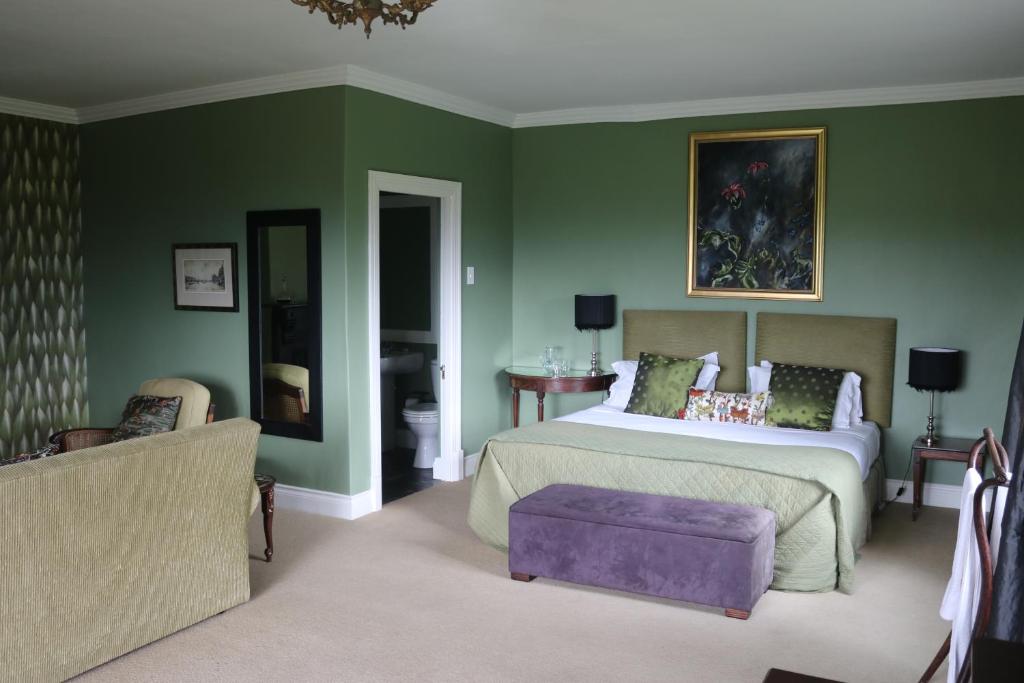 a bedroom with green walls and a bed and a couch at Lastingham Country Lodge in Lidgetton