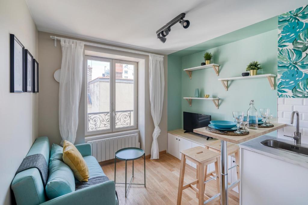 ein Wohnzimmer mit einem blauen Sofa und einer Küche in der Unterkunft HONORÊ - Suite Carnot in Lyon