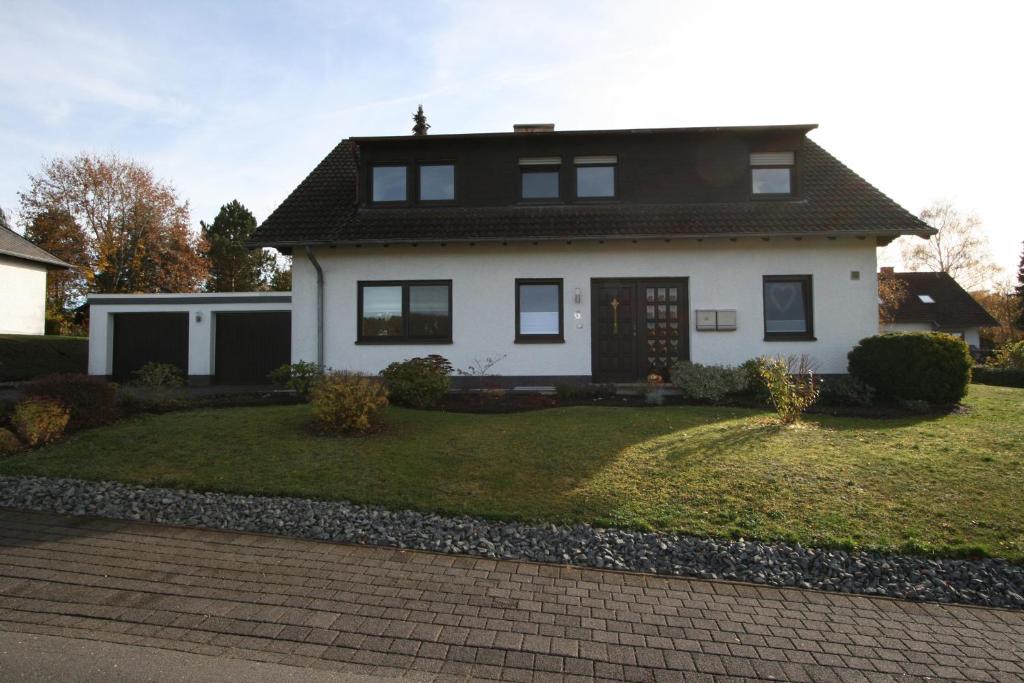 a white house with a yard with a driveway at Munterleyblick in Gerolstein