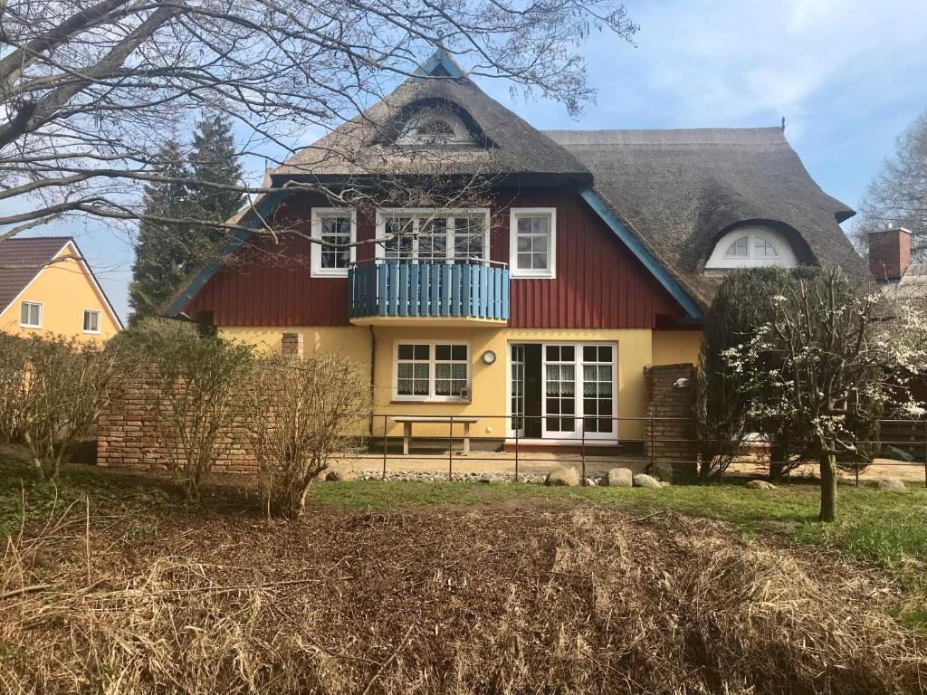 a yellow and red house with a blue balcony at "Bootsmannskammer" by Ferienhaus Strandgut in Born